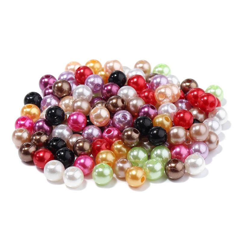 A pile of colorful imitation pearl beads in various shades including pink, red, gold, and green.
