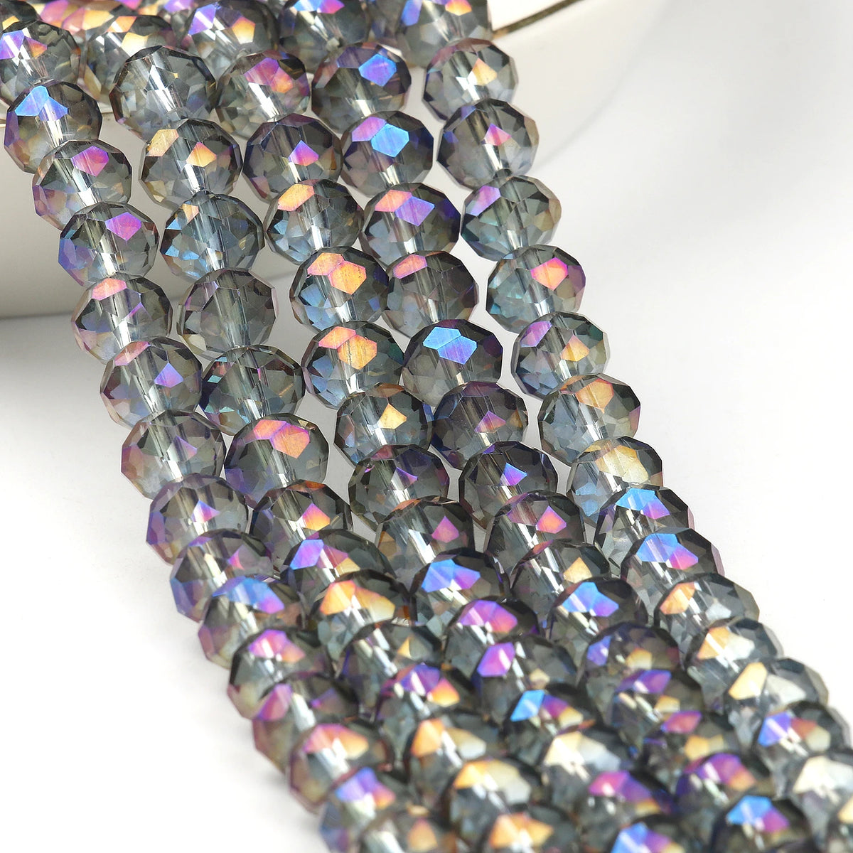 A close-up of dark blue and purple faceted crystal glass beads strung together for jewelry making.