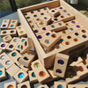 Wooden gemstone building blocks with acrylic crystals arranged in a light wooden box.