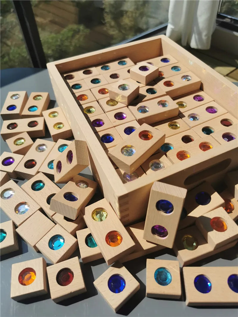 Wooden gemstone building blocks with acrylic crystals arranged in a light wooden box.
