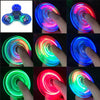 A series of images showing a glow-in-the-dark LED fidget spinner rotating in various colors including blue, pink, green, and 
