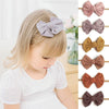 A blonde girl is shown wearing a lavender bow headband, with several other colored bows displayed next to it.