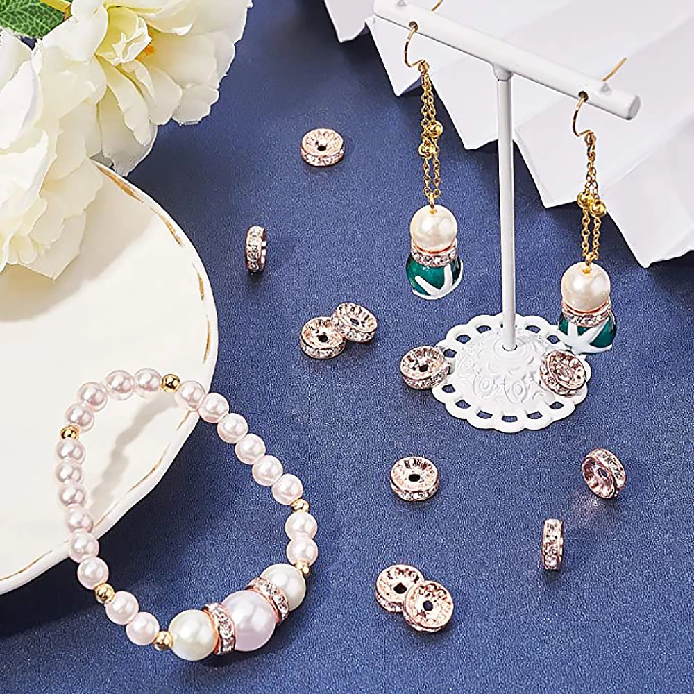 A collection of pearl and crystal rhinestone spacer beads for jewelry making displayed on a dark blue surface.