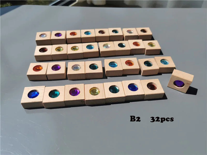 A collection of 32 wooden gemstone building blocks featuring various colored acrylic crystals arranged in rows.