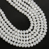 A close-up of a strand of white faceted crystal glass beads arranged in a U shape.
