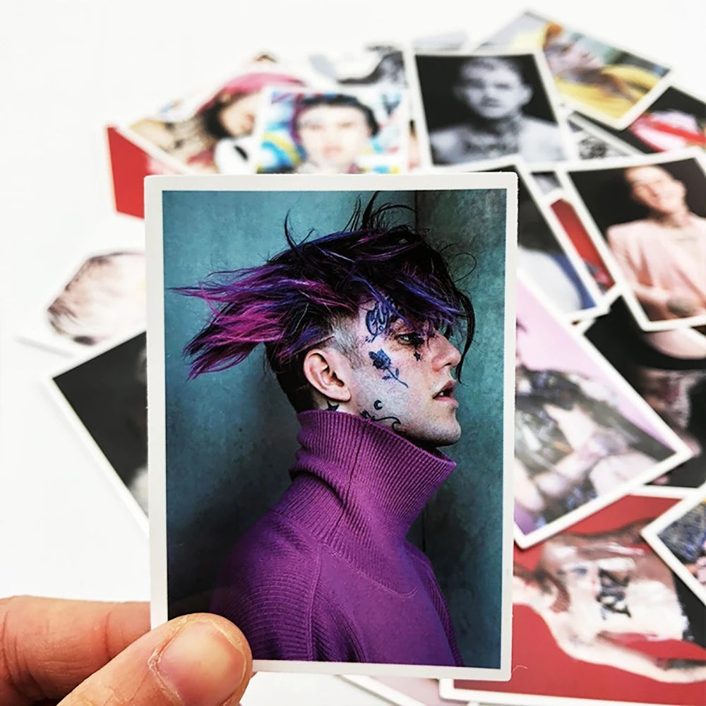 A close-up photo of a person with purple hair and face paint wearing a purple turtleneck, displayed on a white card.