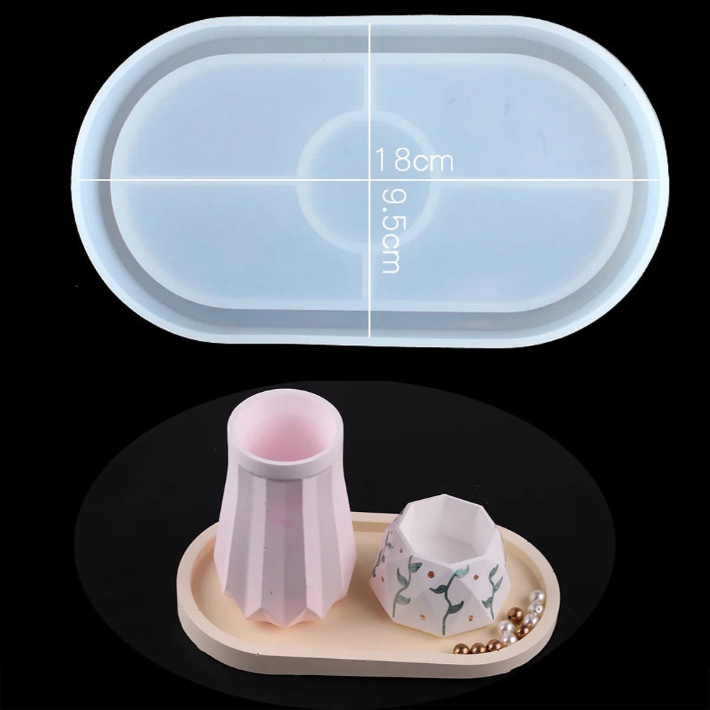 A clear silicone mold with measurement lines is shown above a small pink vase and a white patterned planter on a wooden tray.