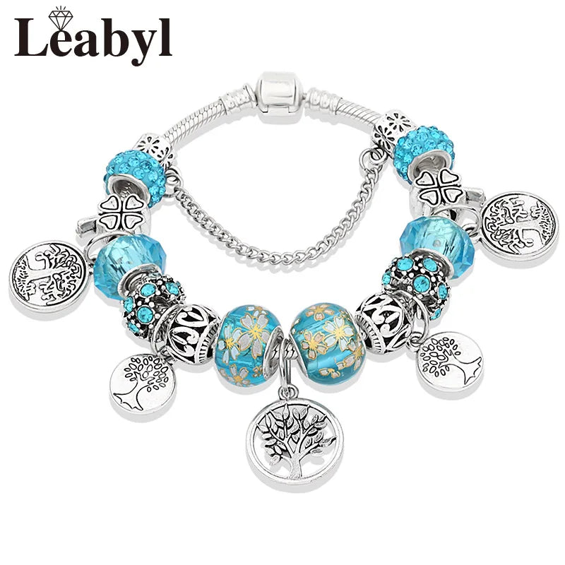 Silver crystal charm bracelet featuring blue and teal beads with intricate tree of life motifs