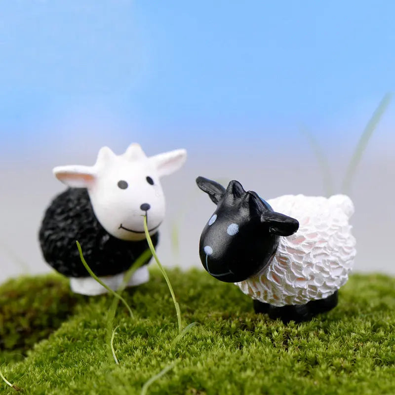 A small black and white sheep figurine standing on green moss against a light blue sky.