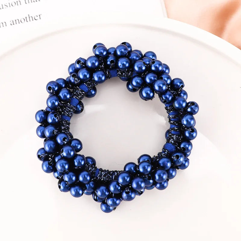 A circular crown of dark blue and navy blue faux pearls used as elegant hair ties or bow scrunchies.