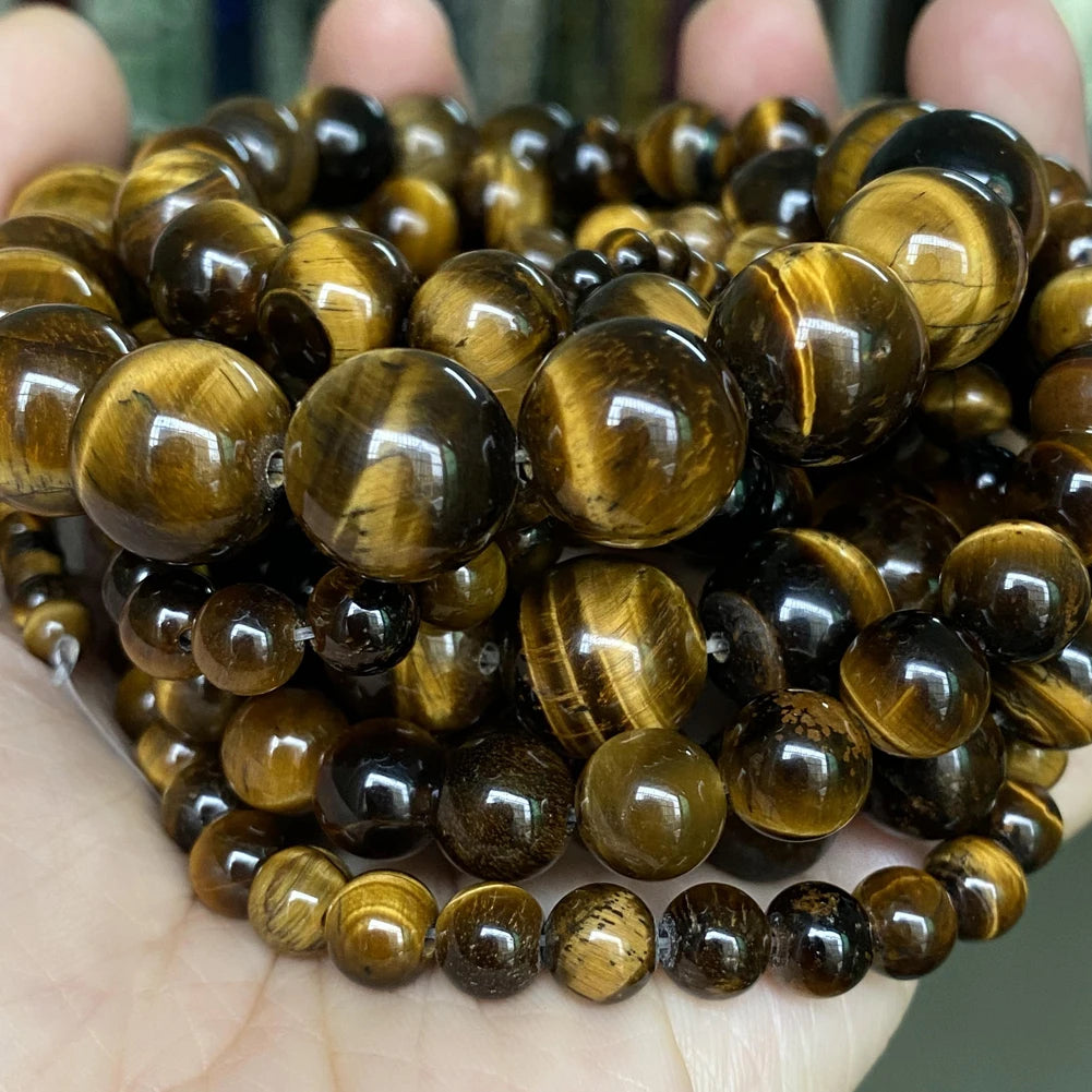 A collection of polished, round tiger eye gemstone beads in various shades of brown and gold.
