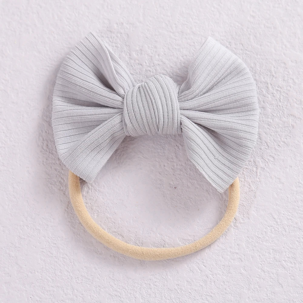 A light gray ribbed bow headband with a beige elastic band, photographed against a white background.
