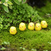A group of small yellow duckling figurines resting on bright green moss.