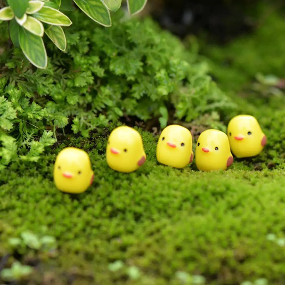 A group of small yellow duckling figurines resting on bright green moss.