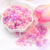A pile of assorted pink and purple pearl beads for jewelry making next to a pink lotus flower.