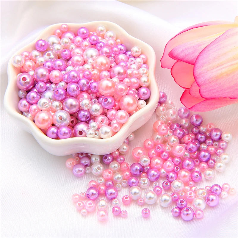 A pile of assorted pink and purple pearl beads for jewelry making next to a pink lotus flower.