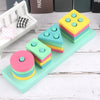 A collection of colorful wooden sensory blocks and a music rattle arranged on a light green tray.