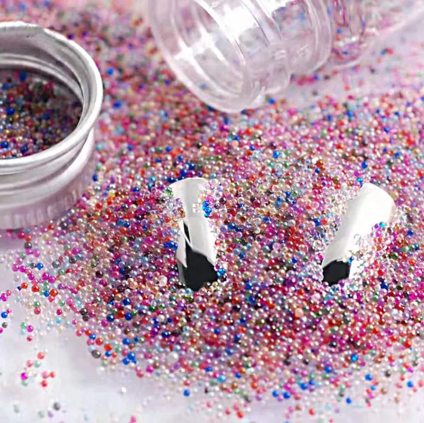 A close-up of iridescent mini glass bubble beads scattered on a white surface next to a clear plastic bottle.