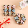 A collection of adorable sloth silicone beads in various shades of gray and pink arranged on a wooden board.