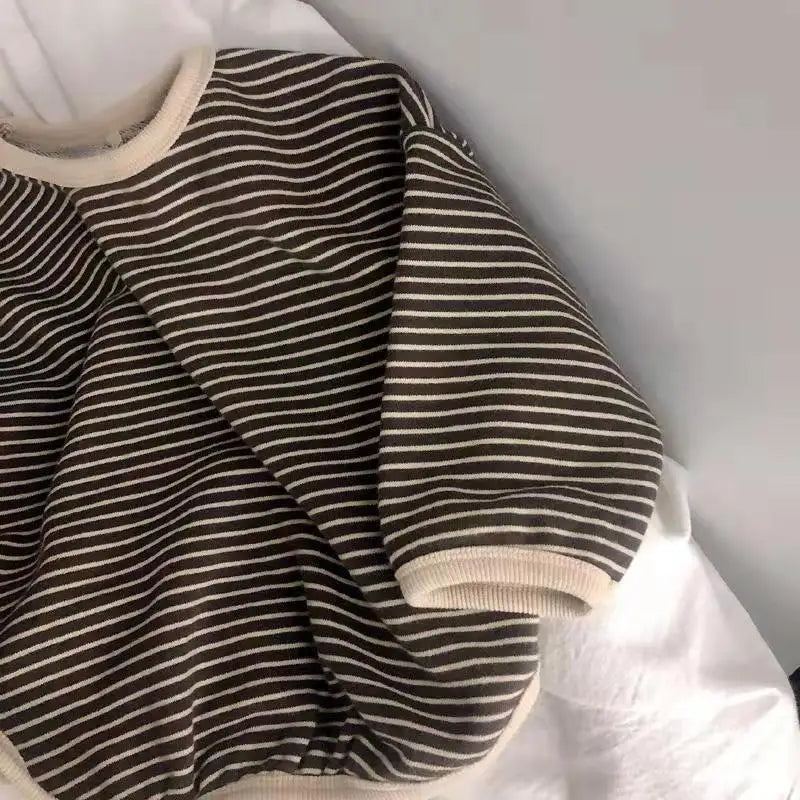 A close-up of a kids cotton pullover sweatshirt with horizontal dark brown and cream stripes.