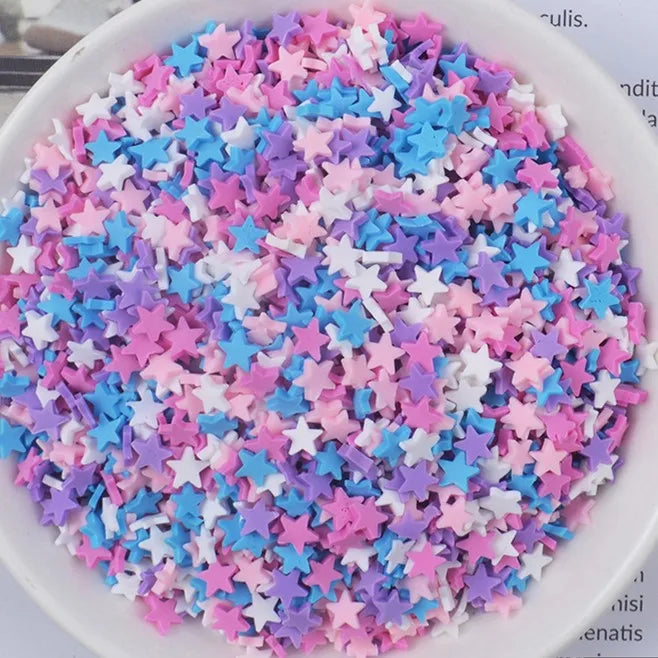 A bowl filled with heart-shaped fake candy sprinkles in various pastel colors like pink, purple, and blue for slime and craft