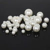A collection of white imitation pearl beads scattered on a dark surface.