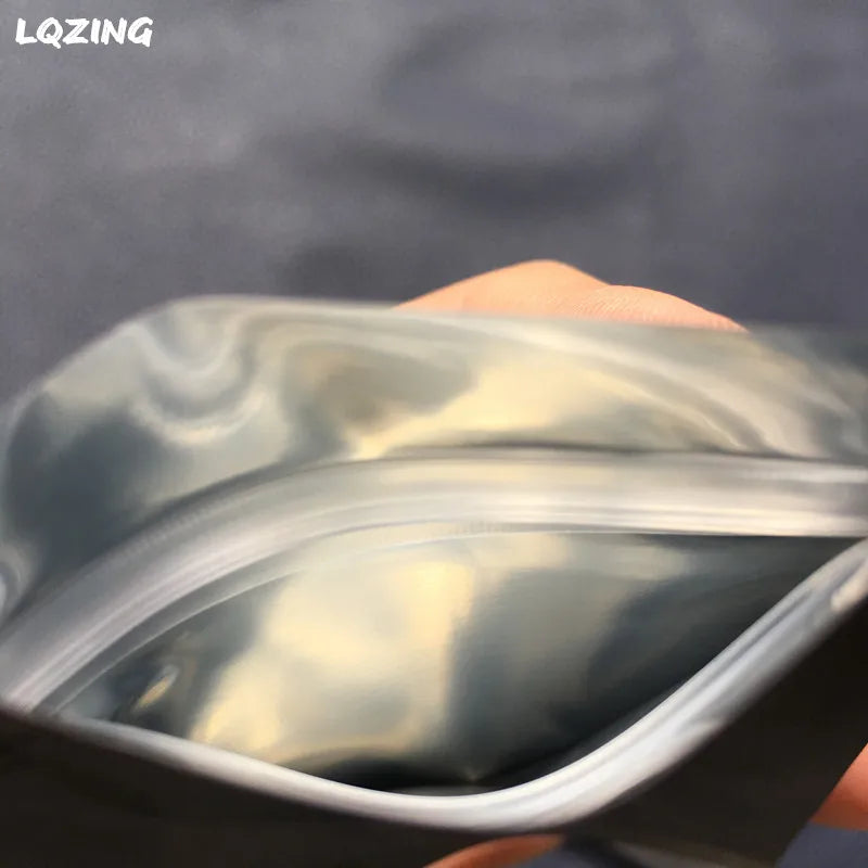 A hand is holding a clear plastic reusable ziplock bag, showing the flexible material and zipper closure.