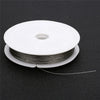 A roll of stainless steel tiger tail beading wire for jewelry making lying on a dark surface.