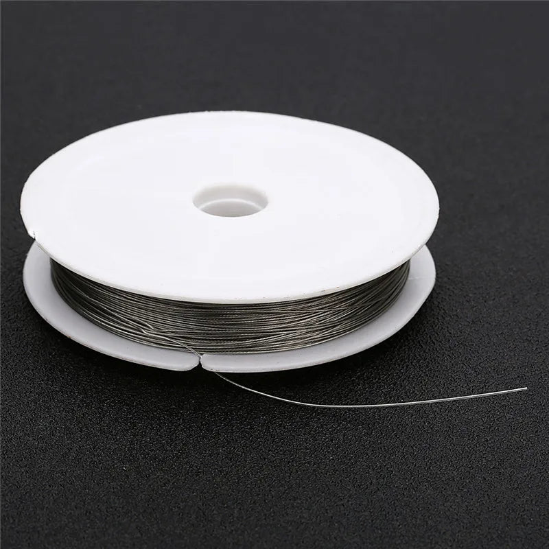 A roll of stainless steel tiger tail beading wire for jewelry making lying on a dark surface.