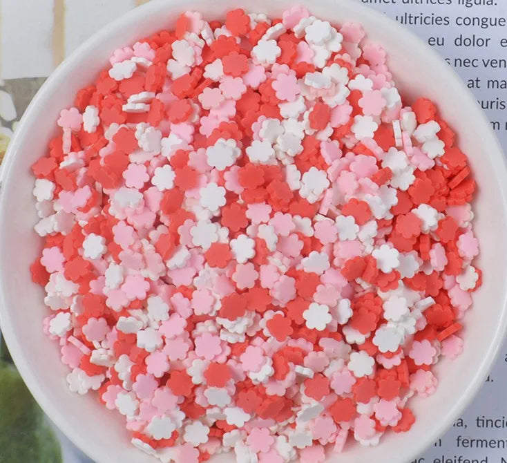 A bowl filled with heart-shaped fake candy sprinkles in shades of pink and white for slime and craft decorations.