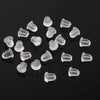 A collection of clear silicone earring backs scattered on a dark surface.