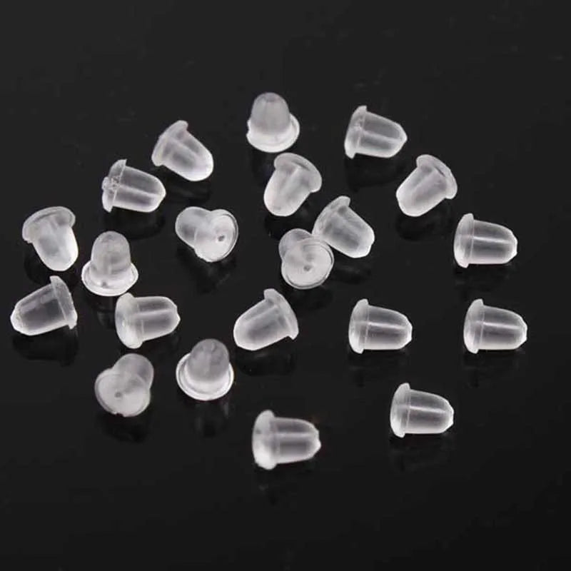 A collection of clear silicone earring backs scattered on a dark surface.