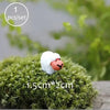 A small white sheep figurine resting on a mossy green surface.
