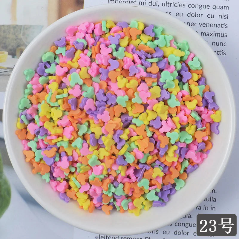A bowl filled with heart-shaped fake candy sprinkles in various bright colors for slime and craft decorations