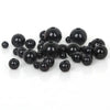 A collection of smooth, black imitation pearl beads scattered on a white surface.