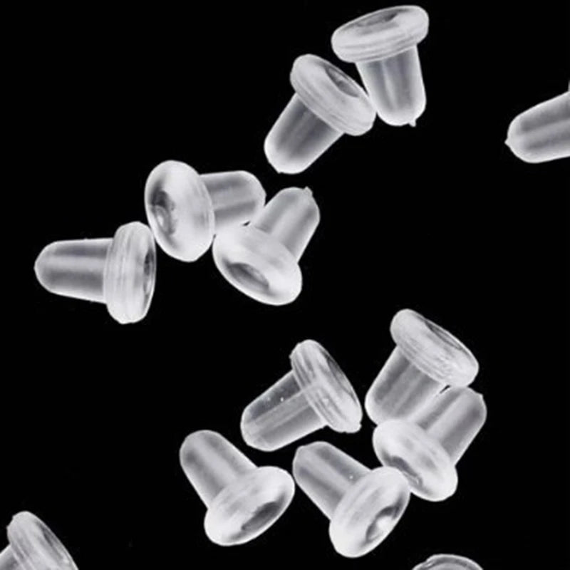 A close-up view of clear silicone earring backs scattered on a black background.