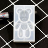 A clear silicone mold shaped like a bear is shown on a black surface.