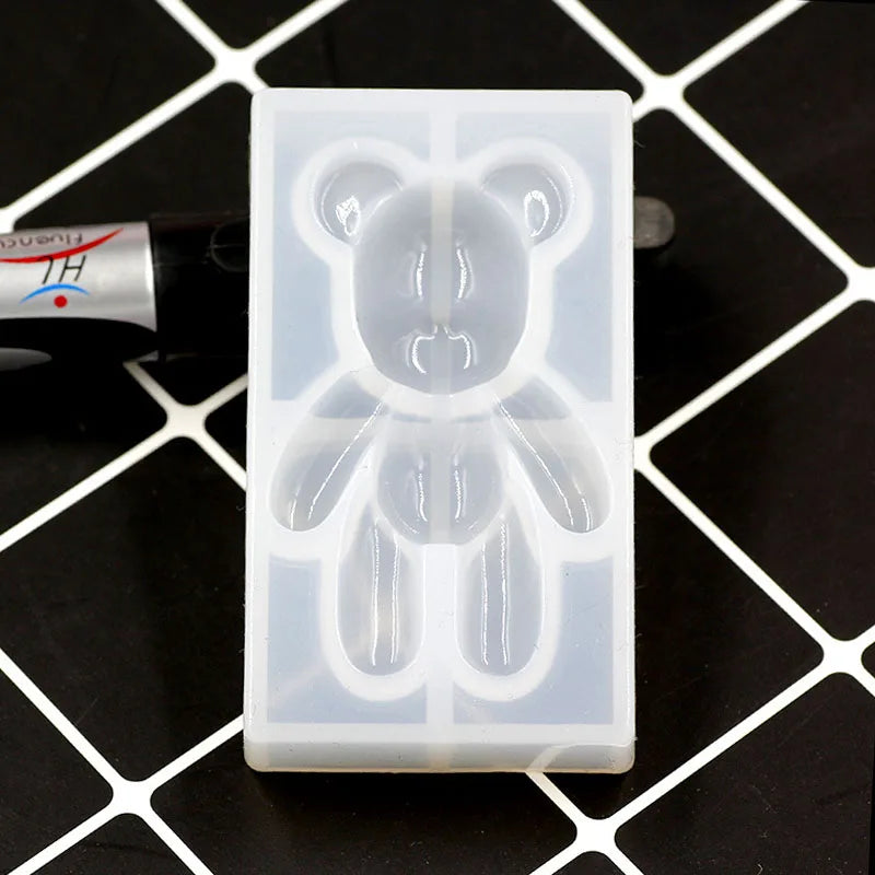A clear silicone mold shaped like a bear is shown on a black surface.