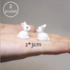 Two small white animal figurines are shown resting on a person's hand.