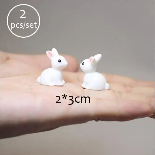 Two small white animal figurines are shown resting on a person's hand.