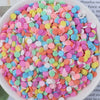A pile of heart-shaped fake candy sprinkles in various pastel colors like pink, blue, and yellow for crafting.