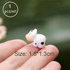 A small white and orange miniature animal figurine is held on a person's finger.