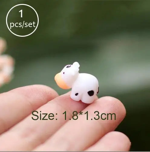 A small white and orange miniature animal figurine is held on a person's finger.