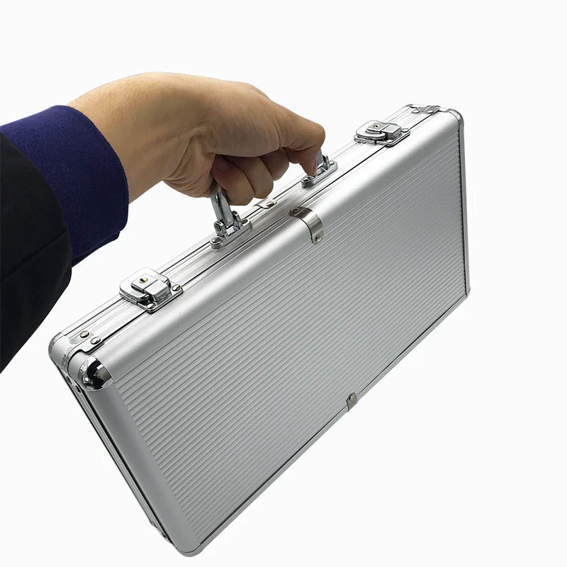 A hand is opening a silver aluminum poker chip carry case with a lock.