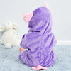 A purple hooded romper resembling a bunny is sitting on a light blue fuzzy surface.