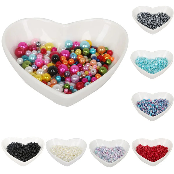 A collection of colorful imitation pearl beads in various shades and sizes, displayed in a heart-shaped bowl.