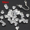 A pile of 50 clear silicone earring backs and a single earring hook are displayed on a dark surface.