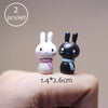 Two small white and black animal figurines are shown resting on a person's finger.