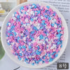 A bowl filled with heart-shaped fake candy sprinkles in various shades of pink, purple, and blue for slime and craft decorati