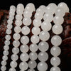 A close-up of natural white crystal quartz round beads arranged in a string for jewelry making.